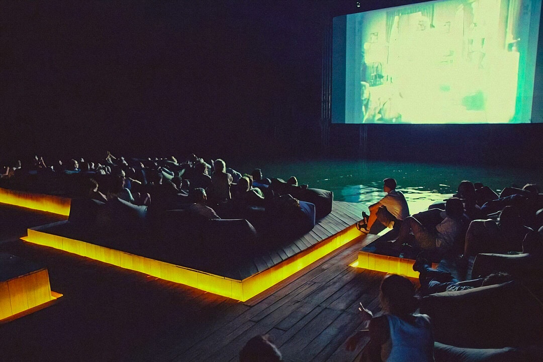 Audience watching films on floating rafts at night during the Archipelago Cinema, a unique outdoor movie theater in Thailand