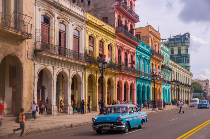 A blue oldtimer taxi is driving through Habana Vieja.