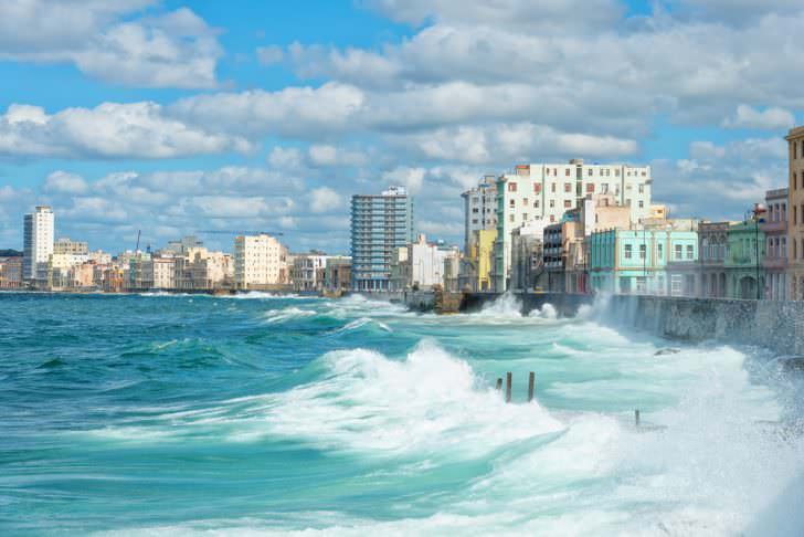 The Havana skyline with big sea waves crashing on the Malecon seawall.