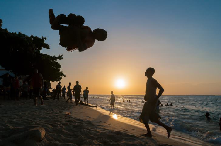 Young african man doing somersaults on the beach in Stone town, Zanzibar