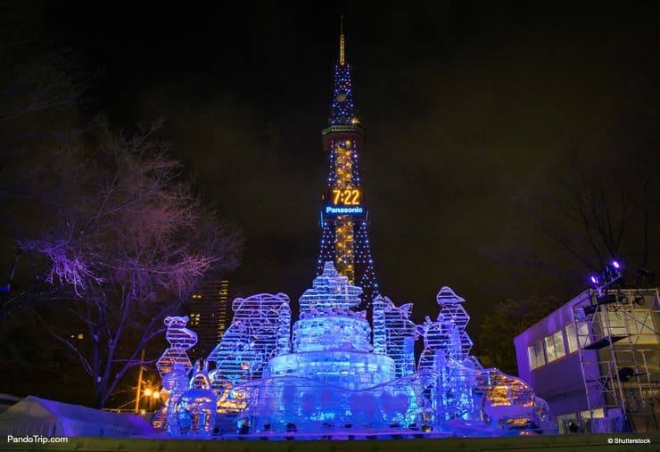 Illuminated snow sculptures during Sapporo Snow Festival with Sapporo TV tower in the background. Sapporo, Hokkaido, Japan