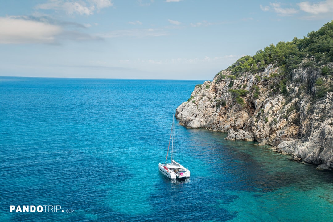 Catamaran anchored in the clear blue-green waters of Cala d’en Serra, Ibiza