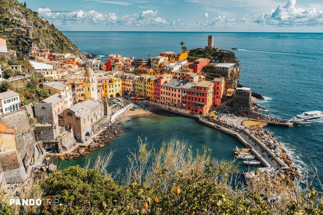 Panoramic view of Vernazza with colorful buildings, the church tower, harbor, and coastline