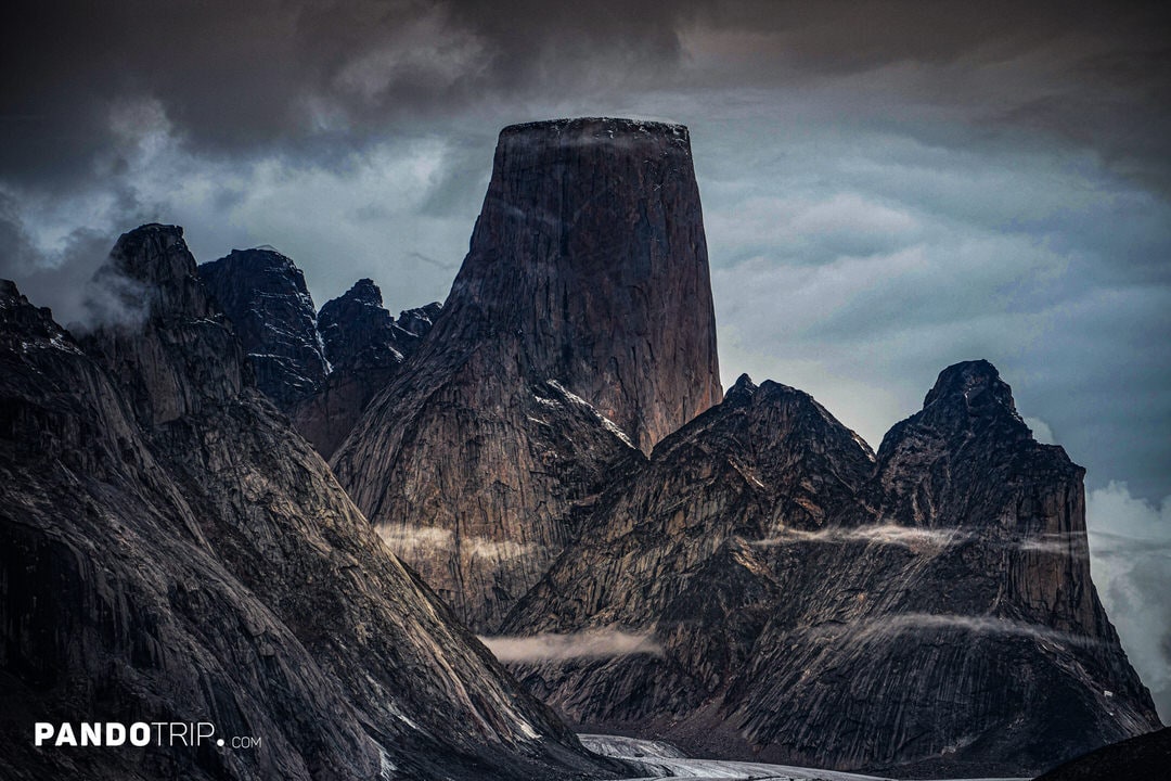 Dark, moody view of Mount Asgard surrounded by mist and jagged Arctic peaks