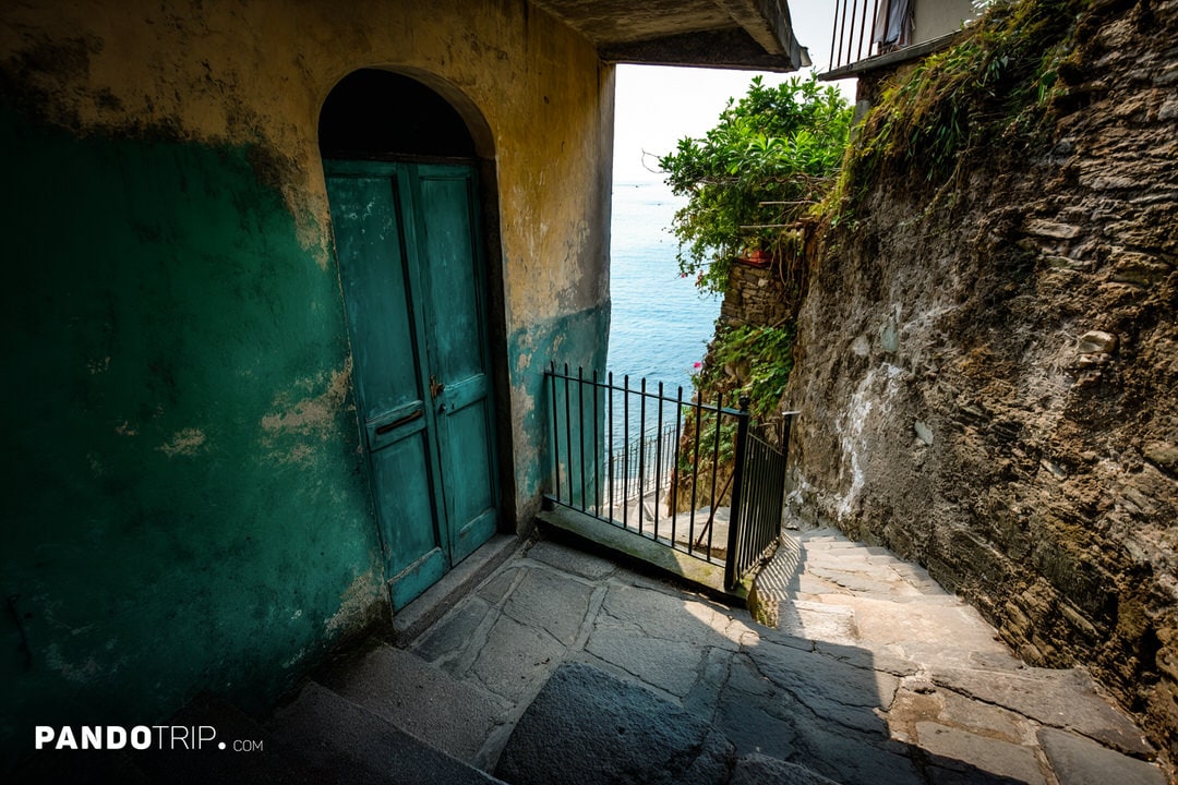 A turquoise door and gated stairway leading down to the sea in Vernazza