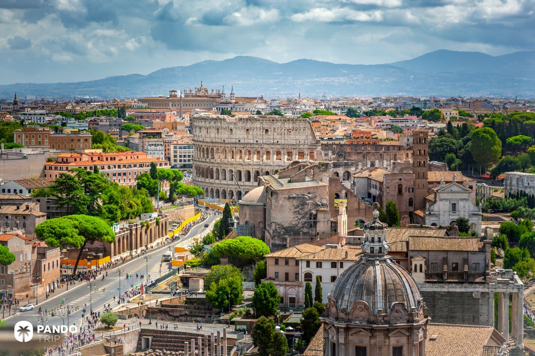 Wide-angle aerial view of the Colosseum and surrounding ruins in central Rome