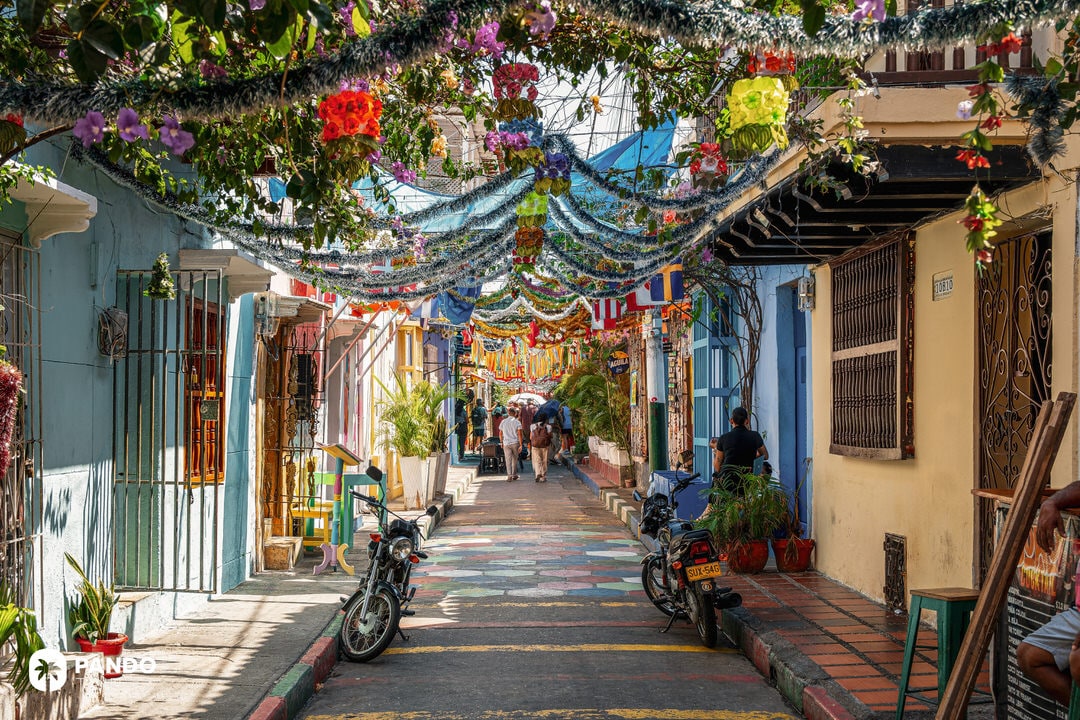 Decorated narrow street in Getsemaní, Cartagena, with colorful flags, flowers, and hanging lights