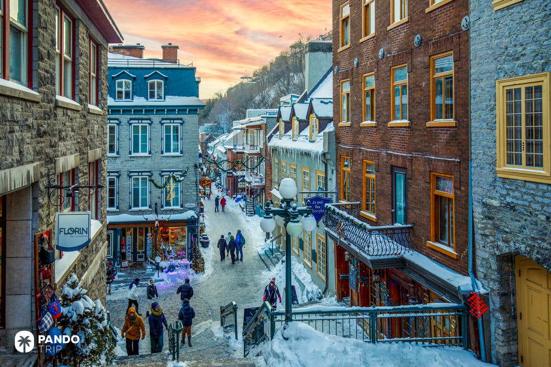 Snow-covered pedestrian street in Old Quebec with historic stone buildings and Christmas decorations