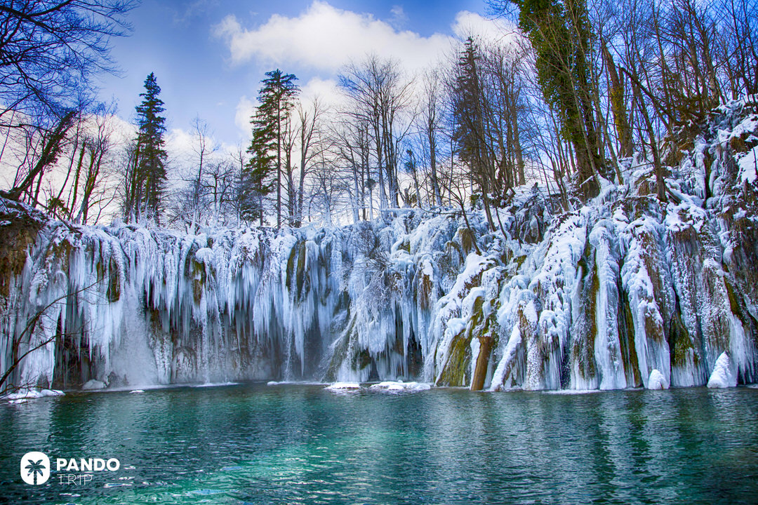 Close-up of a frozen waterfall at Plitvice Lakes during winter with icicles hanging over a turquoise lake