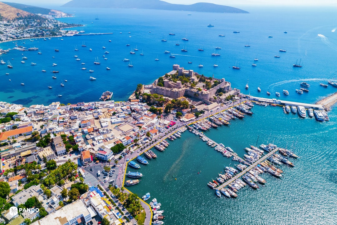 Aegean harbour panorama with Bodrum Castle and dozens of yachts in turquoise water.
