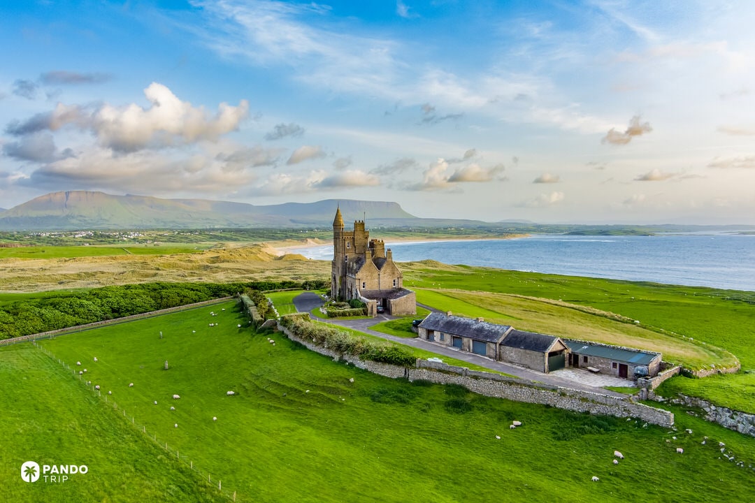 Isolated Classiebawn Castle against Benbulben mountain and Atlantic coastline.