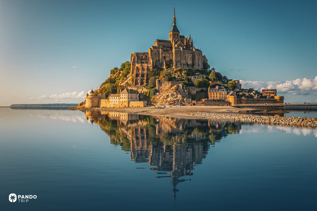 Mont Saint-Michel and its reflection on tidal flats at low tide in Normandy.