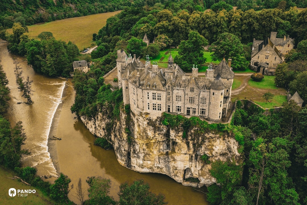 Walzin Castle perched on a limestone cliff above a bend of the Lesse River in Belgium.
