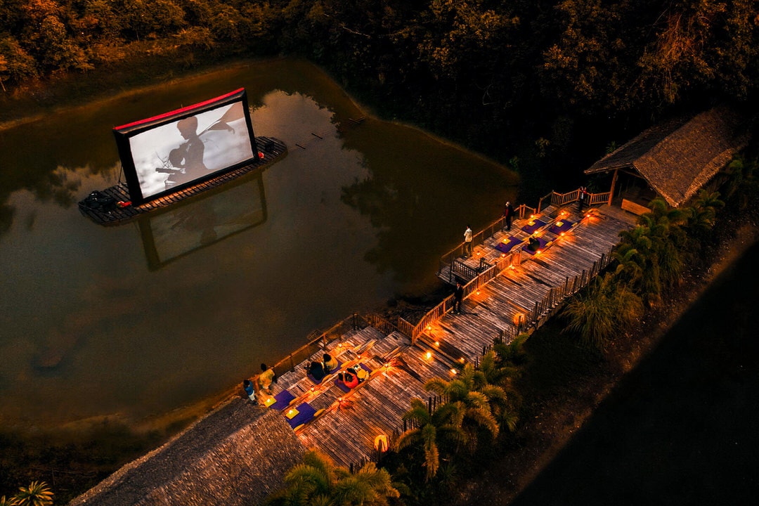 Aerial view of Cinema Paradiso at Soneva Kiri, with wooden deck seating and floating screen on a lagoon in Koh Kood, Thailand