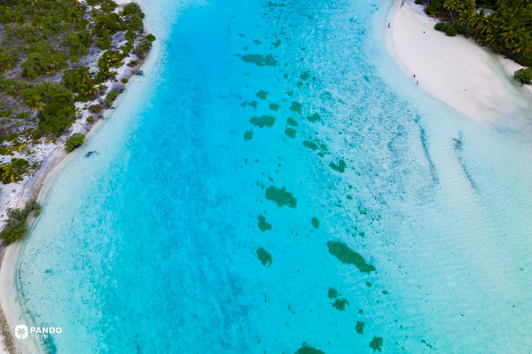 Shallow turquoise waters of Aitutaki Lagoon next to One Foot Island in the Cook Islands