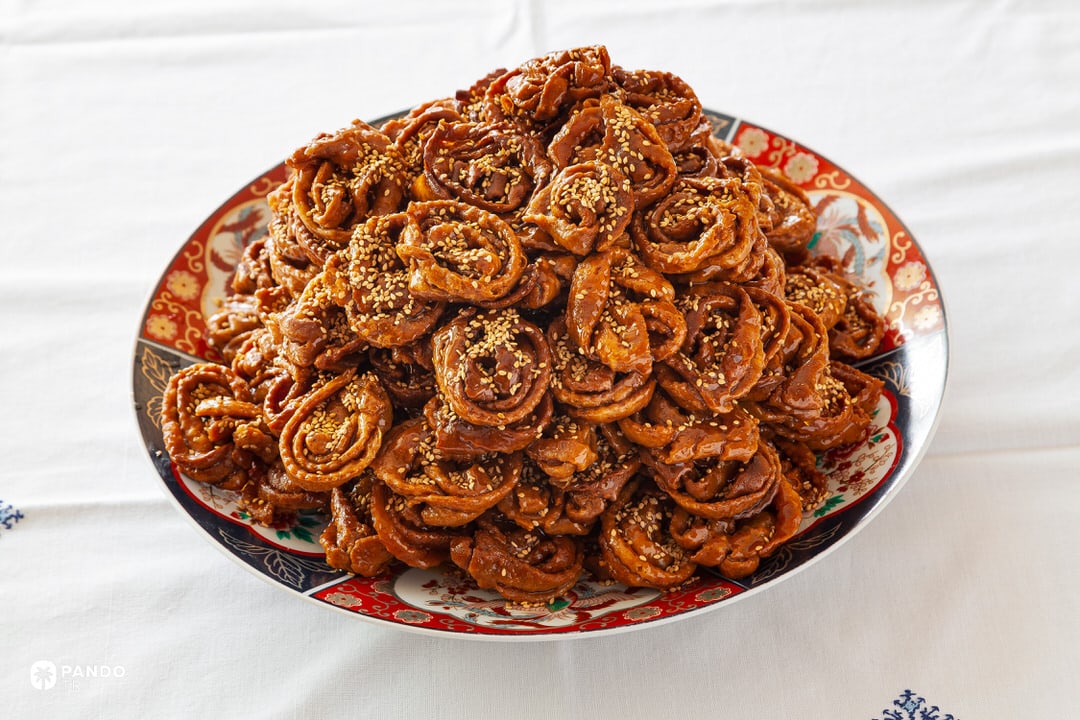Close-up of Moroccan chebakia pastries coated in honey and sprinkled with sesame seeds, served in Chefchaouen