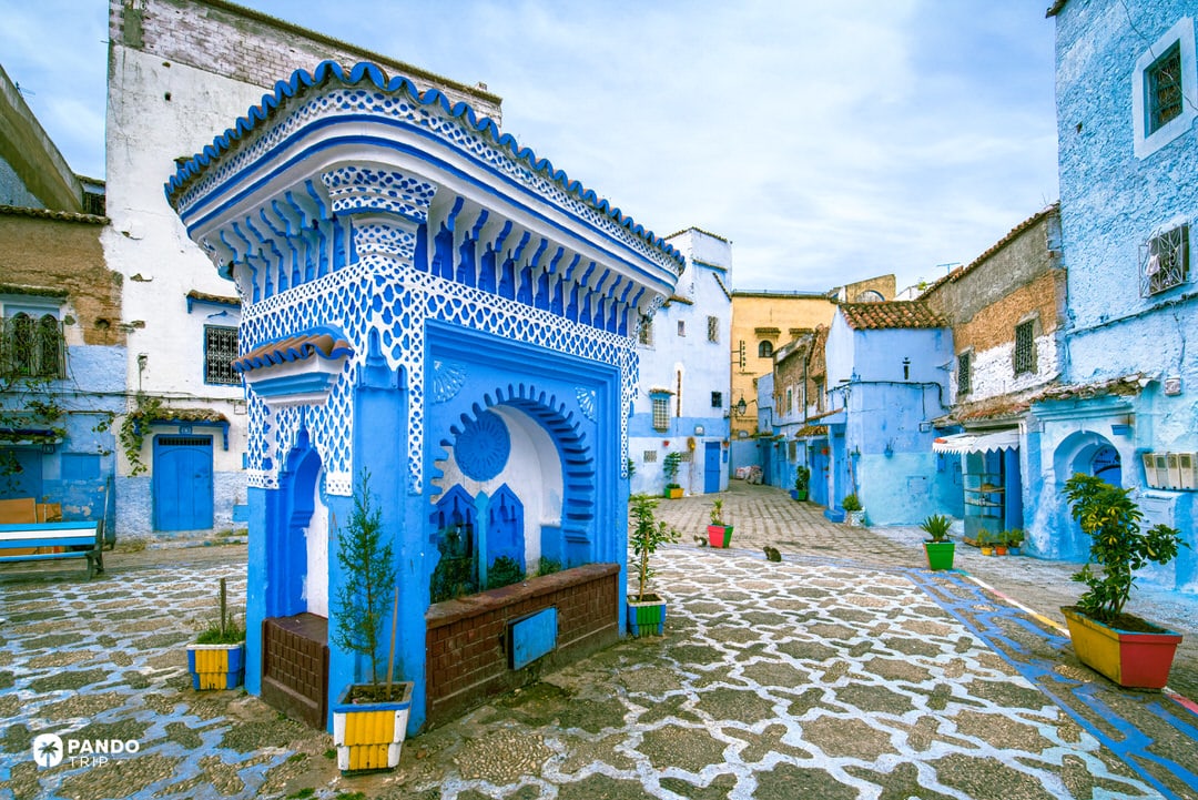 Traditional blue-and-white public fountain in Place El Haouta square, Chefchaouen