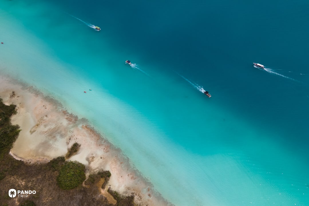 Aerial photo of boats crossing the turquoise waters of Laguna Bacalar in Mexico