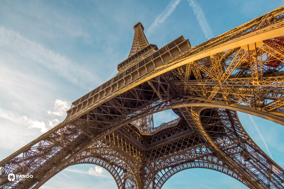 Looking up from the base of the Eiffel Tower in Paris, showing its iron latticework and arch.