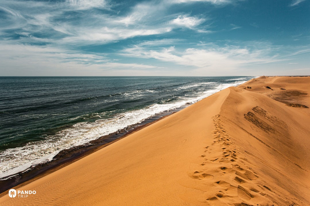 Sand dunes of the Namib Desert meeting the Atlantic Ocean at Walvis Bay, Namibia`